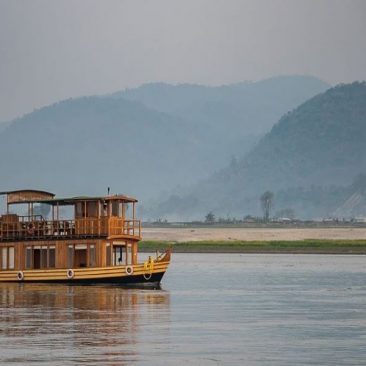 MV Rudra Singha Hausboot auf dem Brahmaputra mit blauschimmernden Bergen am Horizont